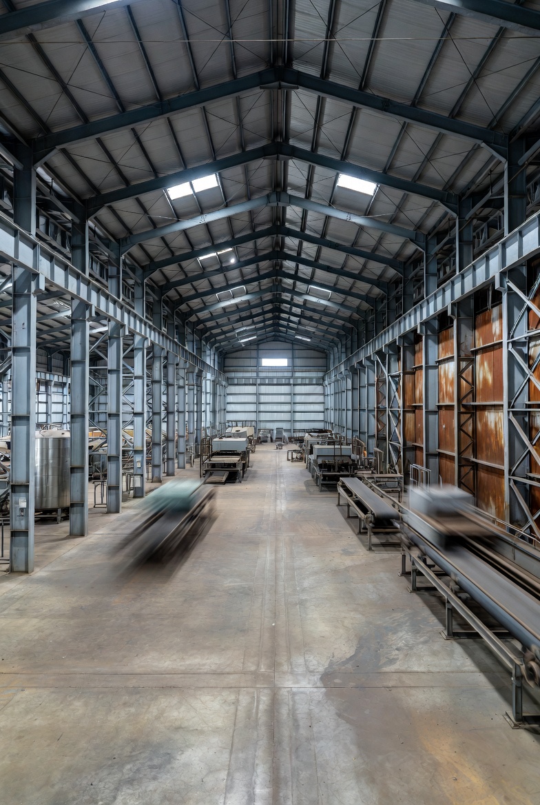 Foto af indersiden af et stort lager med højt til loftet, metalrammer og forskellige lagerinstallationer.